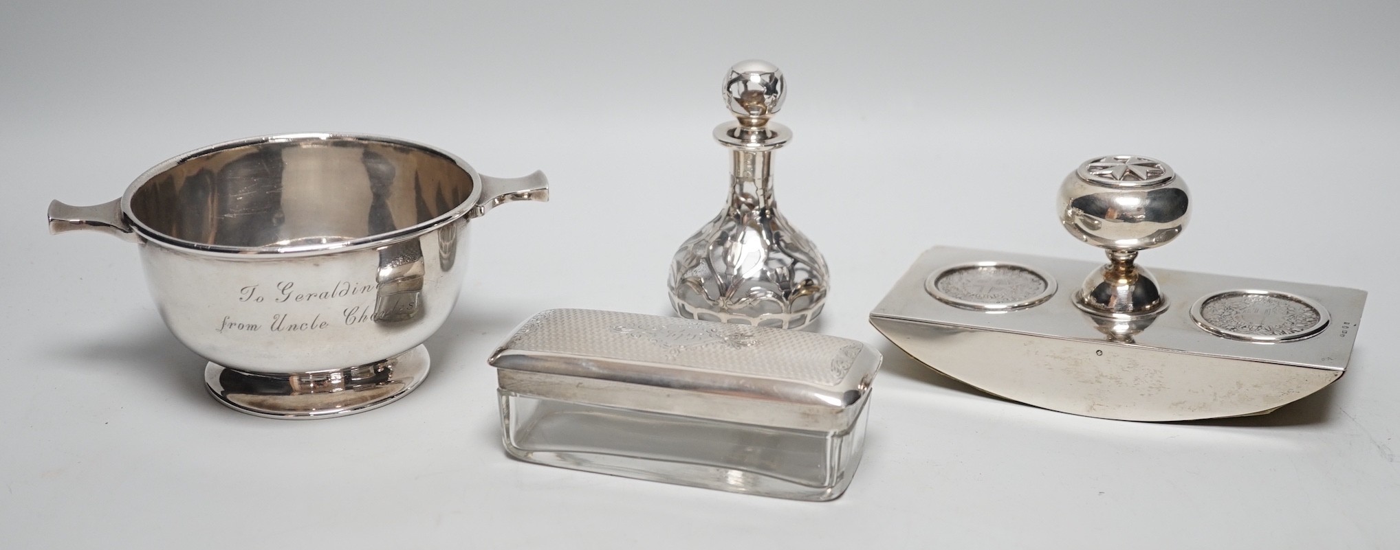 A George V silver two handled bowl, 14.6cm over handles, a white metal overlaid glass scent bottle (a.f.), a silver mounted blotter and a silver mounted glass toilet jar.